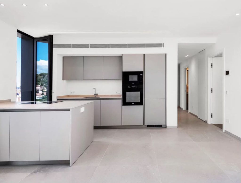 Cocina con isla, muebles claros y electrodomésticos integrados