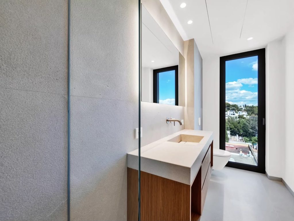 Baño con lavabo, espejo y ventana exterior